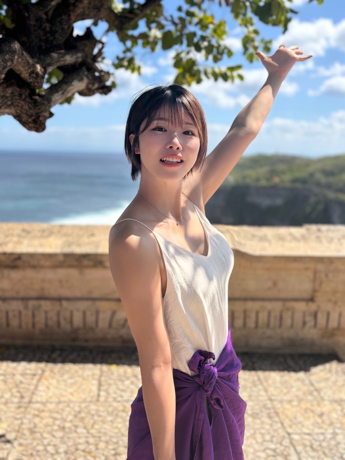 海辺で笑顔を見せて片手を上げるCHIAKI
